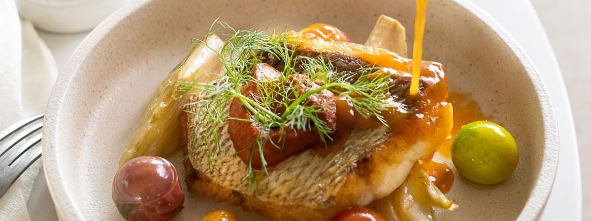 Pan-seared fish with sauce and vibrant garnishes served in The Marke Kitchen at Novotel Sydney International Airport