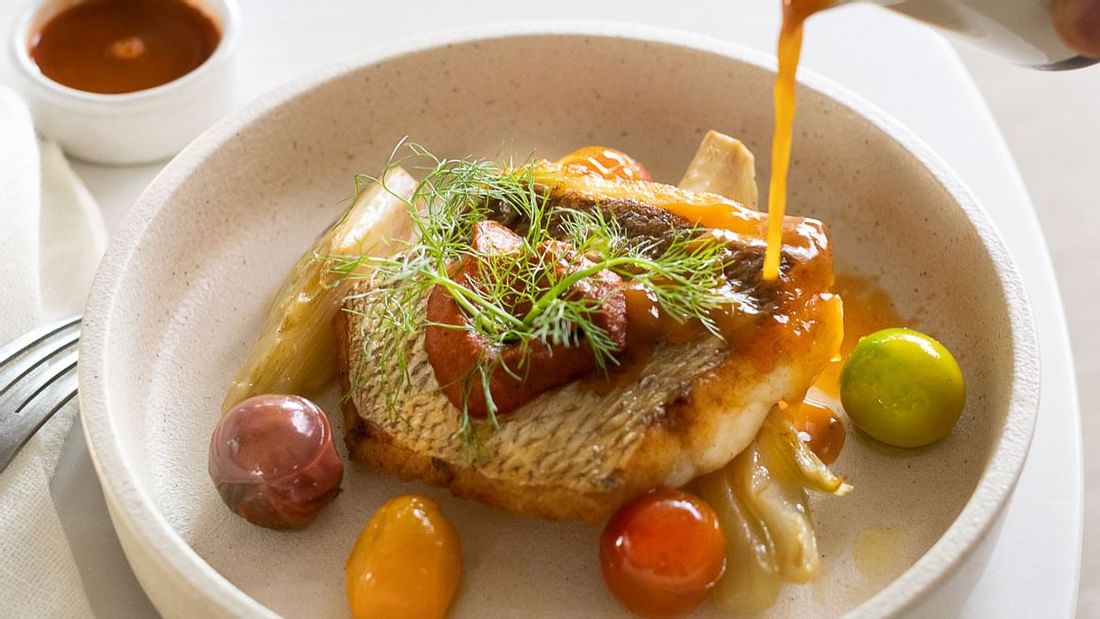 Pan-seared fish with sauce and vibrant garnishes served in The Marke Kitchen at Novotel Sydney International Airport