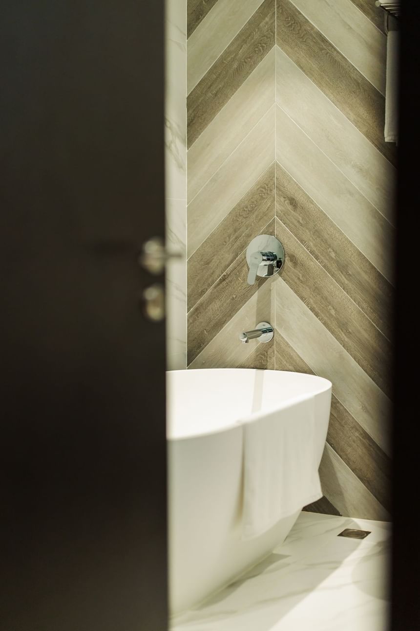 浴室內有一個白色浴缸，上面放著毛巾，牆上有木紋設計和水龍頭。