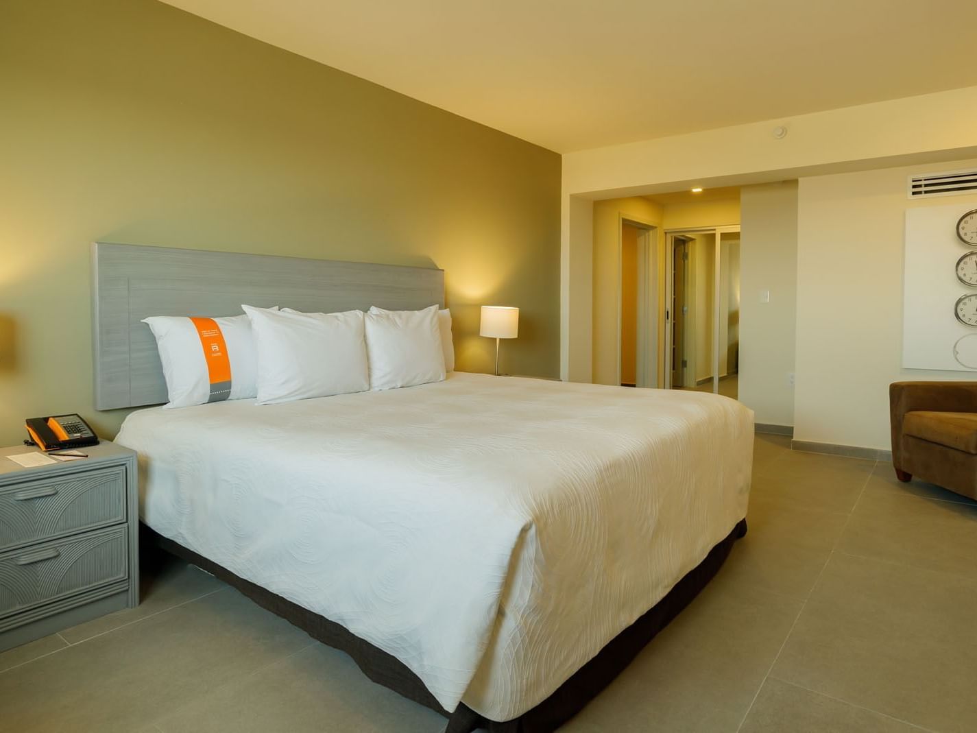 King Master Suite showing a king bed and a wall with three decorative world clocks at Real Inn Mexicali