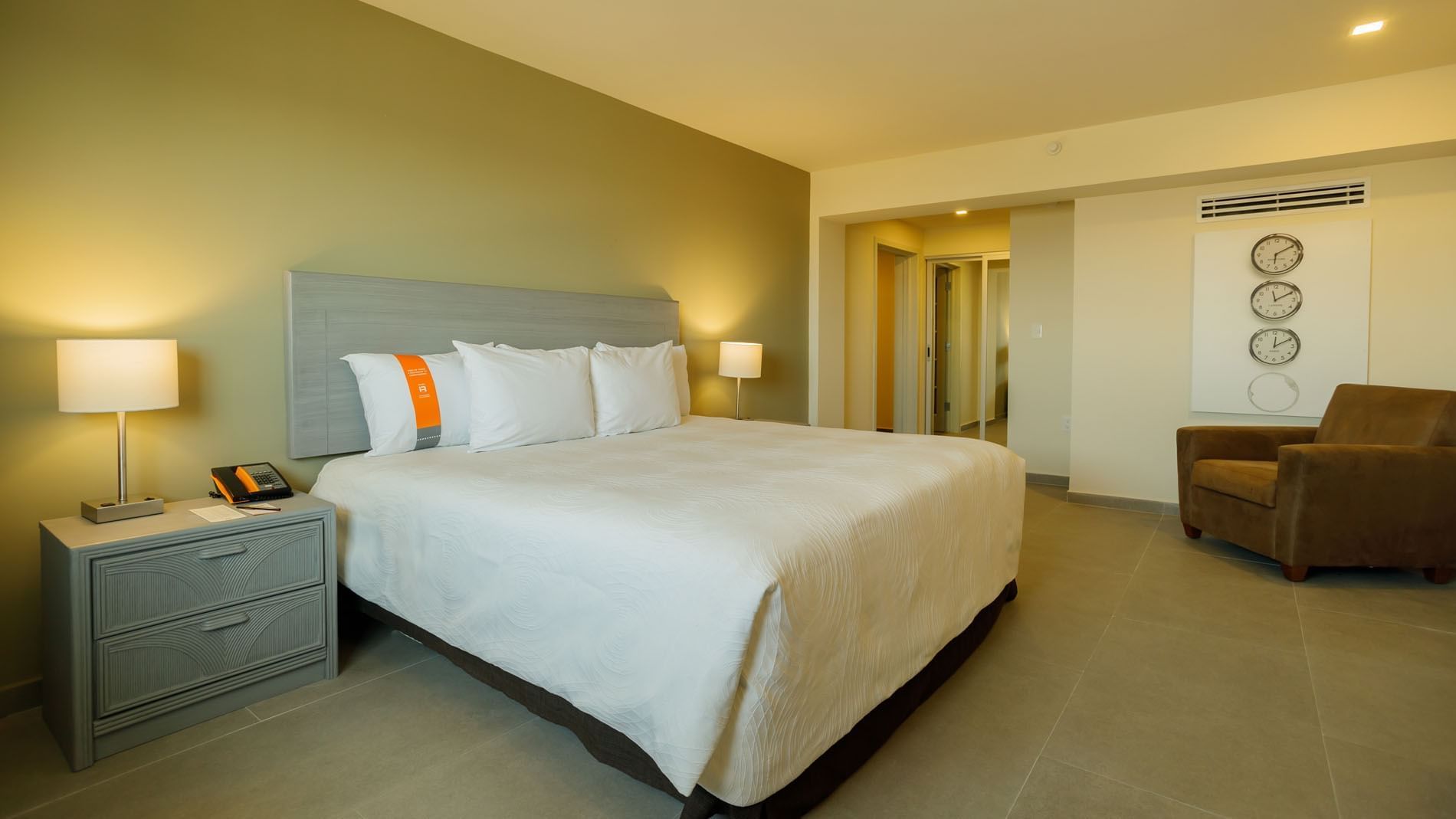 King Master Suite showing a king bed and a wall with three decorative world clocks at Real Inn Mexicali