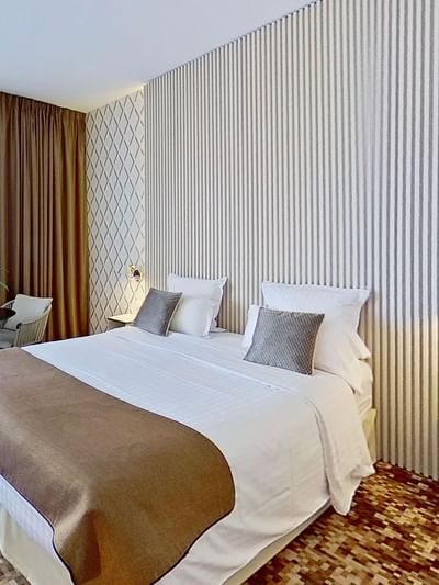 Chambre élégante avec lit double, deux lampes murales, et un coin salon