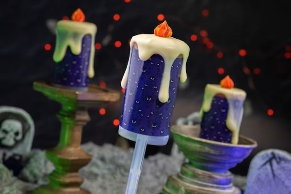 Dark purple cake pops that look like candlesticks dripping with frosting that looks like wax.
