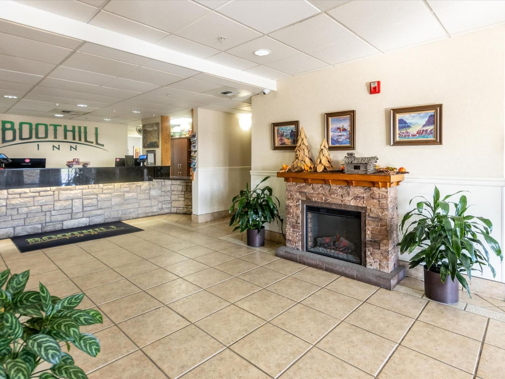 Front desk & fireplace by the lobby area at Boothill Inn & Suites