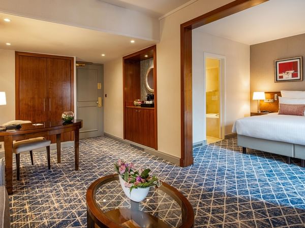 Elegant hotel room with large bed, wooden desk, and floral centerpiece at Warwick Grand-Place Brussels.