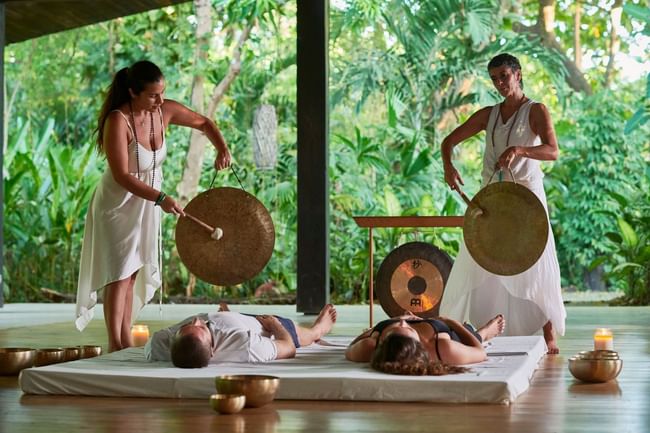 Two instructors lead a peaceful gong meditation for a couple on mats in Lahari Wellness Center at Cala Luna Boutique Hotel