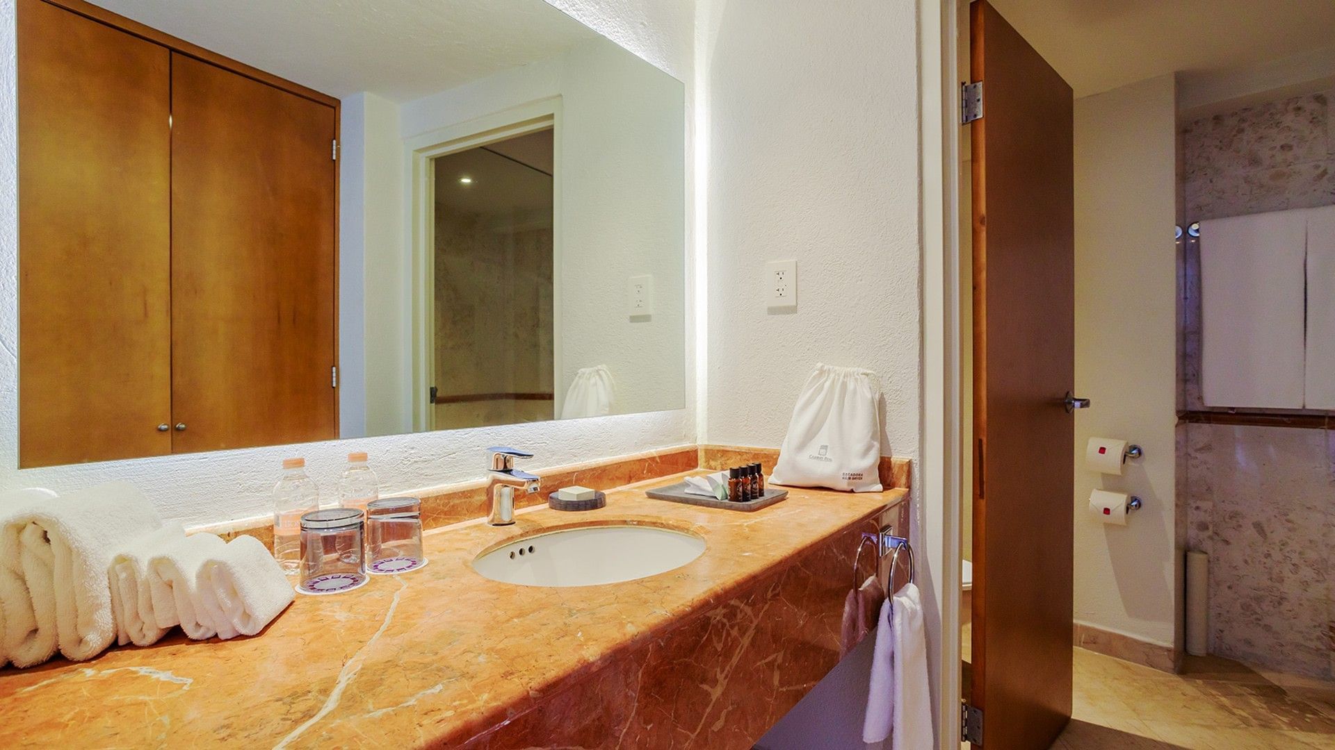 King Camino Real Club bathroom marble sink with high-end amenities, fresh towels, and a lit mirror at Camino Real Veracruz