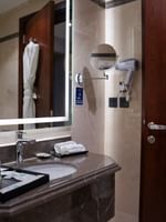 Elegant bathroom with a marble sink and white bathrobe at Warwick Hotel & Spa Jeddah.