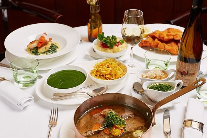 Table in a restaurant set with numerous traditional Viennese dishes accompanied by matching wine