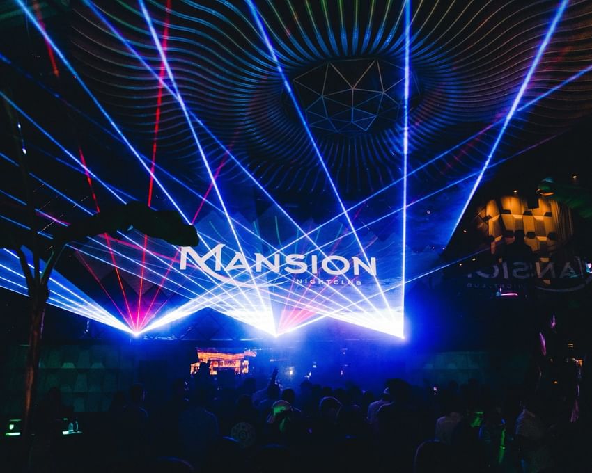 Crowd of people at Paradox Vancouver nightclub with blue and red laser lights and Mansion logo.