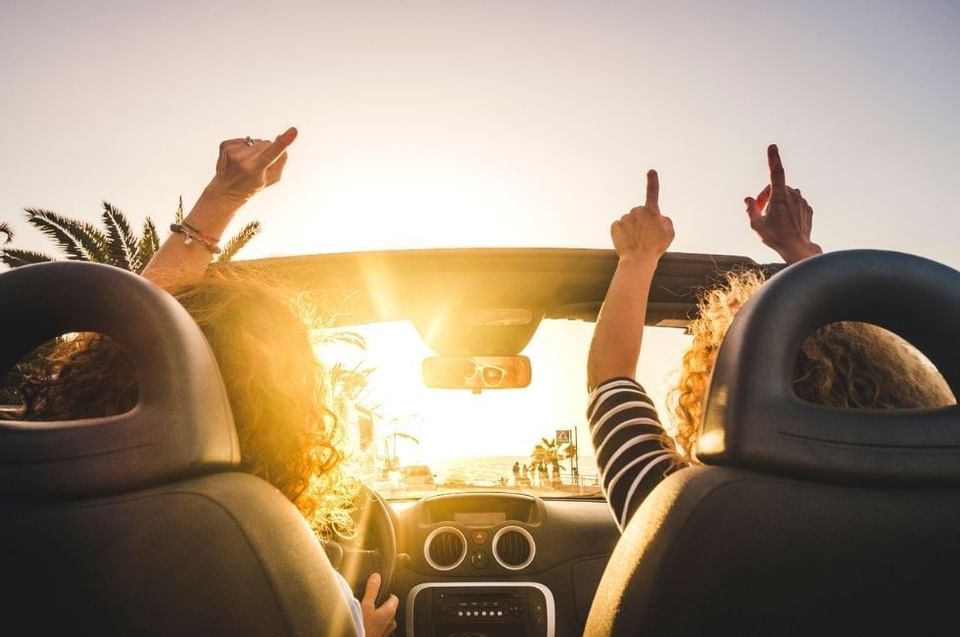 Couple raising their hands in a car at Amora Hotel Sydney