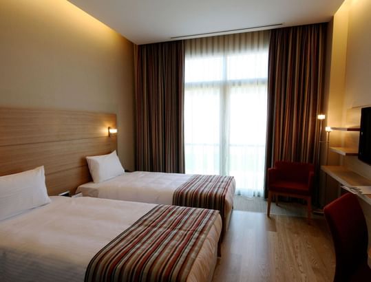 Twin beds, chairs and a work area with TV in the Superior Room at Titanic Anadolu Gebze