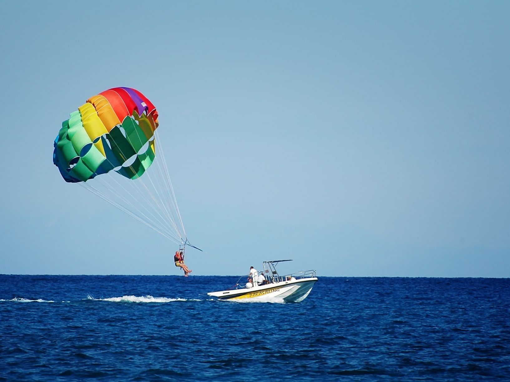 A man parasailing in the sea near ICONA Hotel Windrift