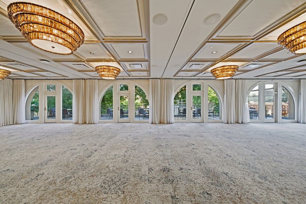 an empty ballroom featuring tons of natural light, and chandeliers