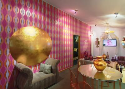 Vibrant room with patterned wallpaper, golden circular wall art and stylish furniture at The Roxbury
