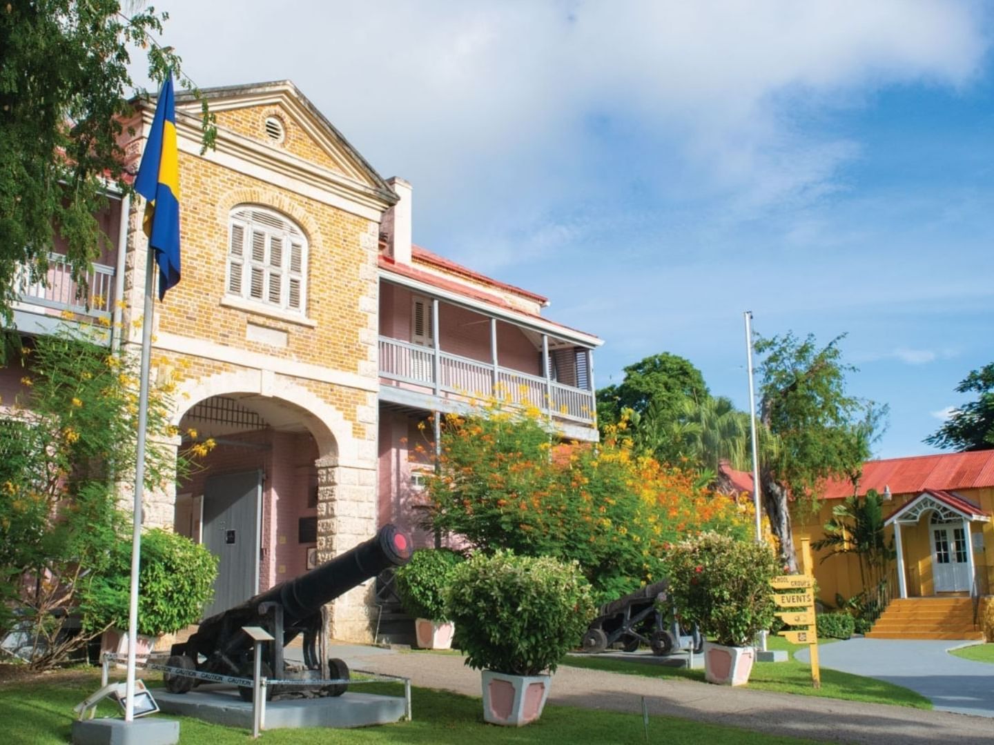 Cannons displayed outside a historic building with lush greenery and a flag at Savannah Beach Hotel.
