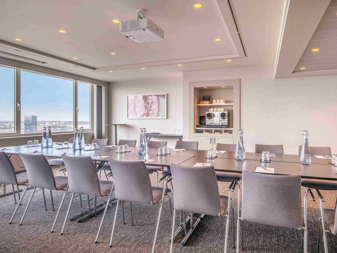 Meet 25 one meeting room with a large table, chairs, and city view through windows at The Hotel Brussels