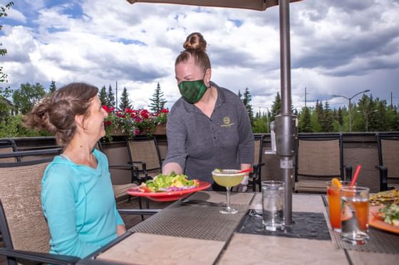 The waitress serves food for the woman at Sophie Station Suites