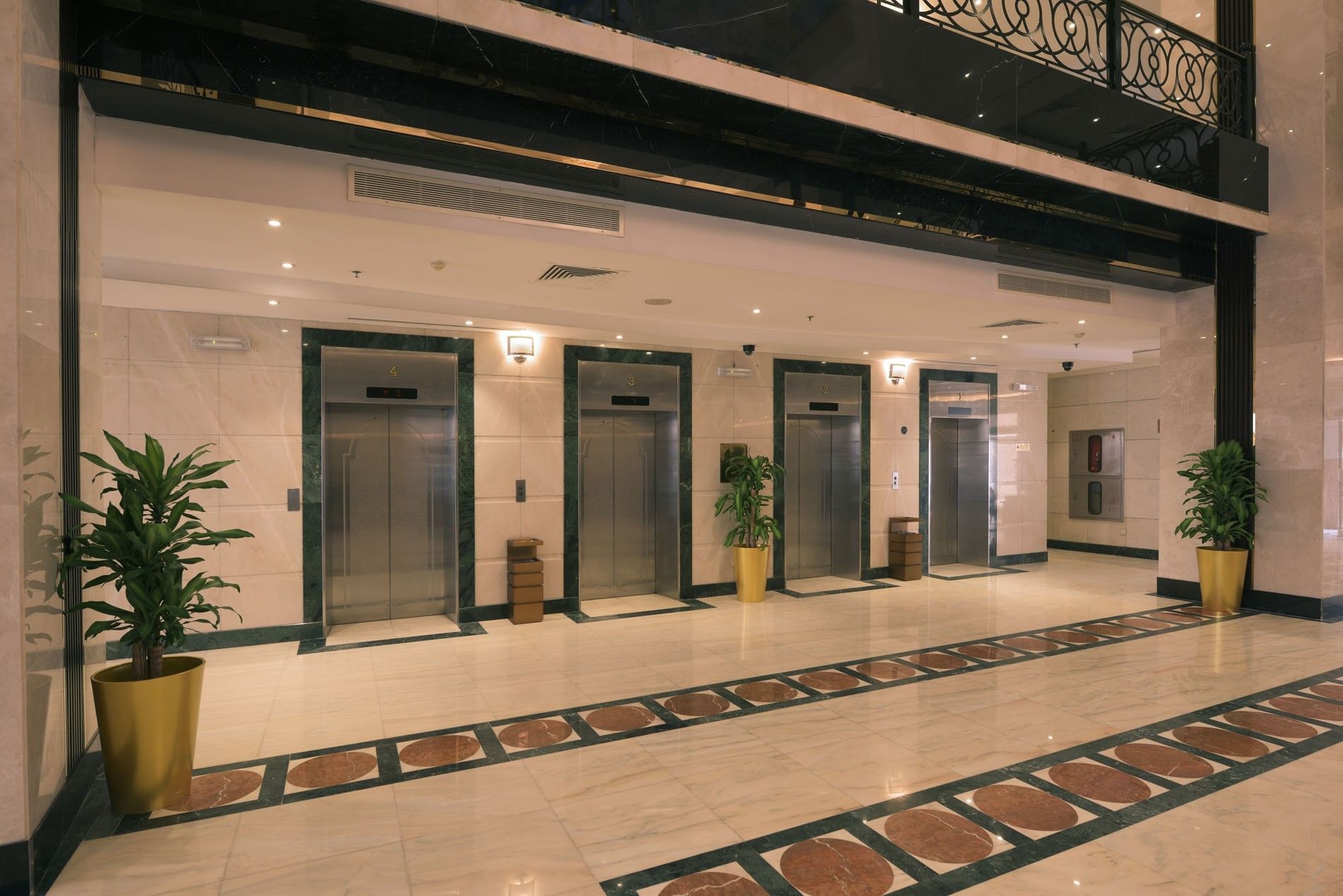Hotel elevator lobby with marble floors, green plants, and four stainless doors at Saja Warwick Madinah