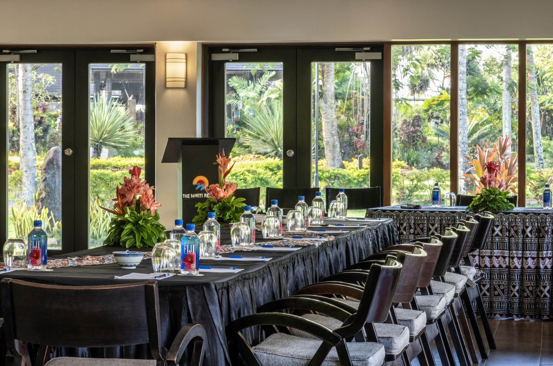 Meeting table with wooden chairs under a wall light near garden view windows in Meeting Talei at The Naviti Resort - Fiji