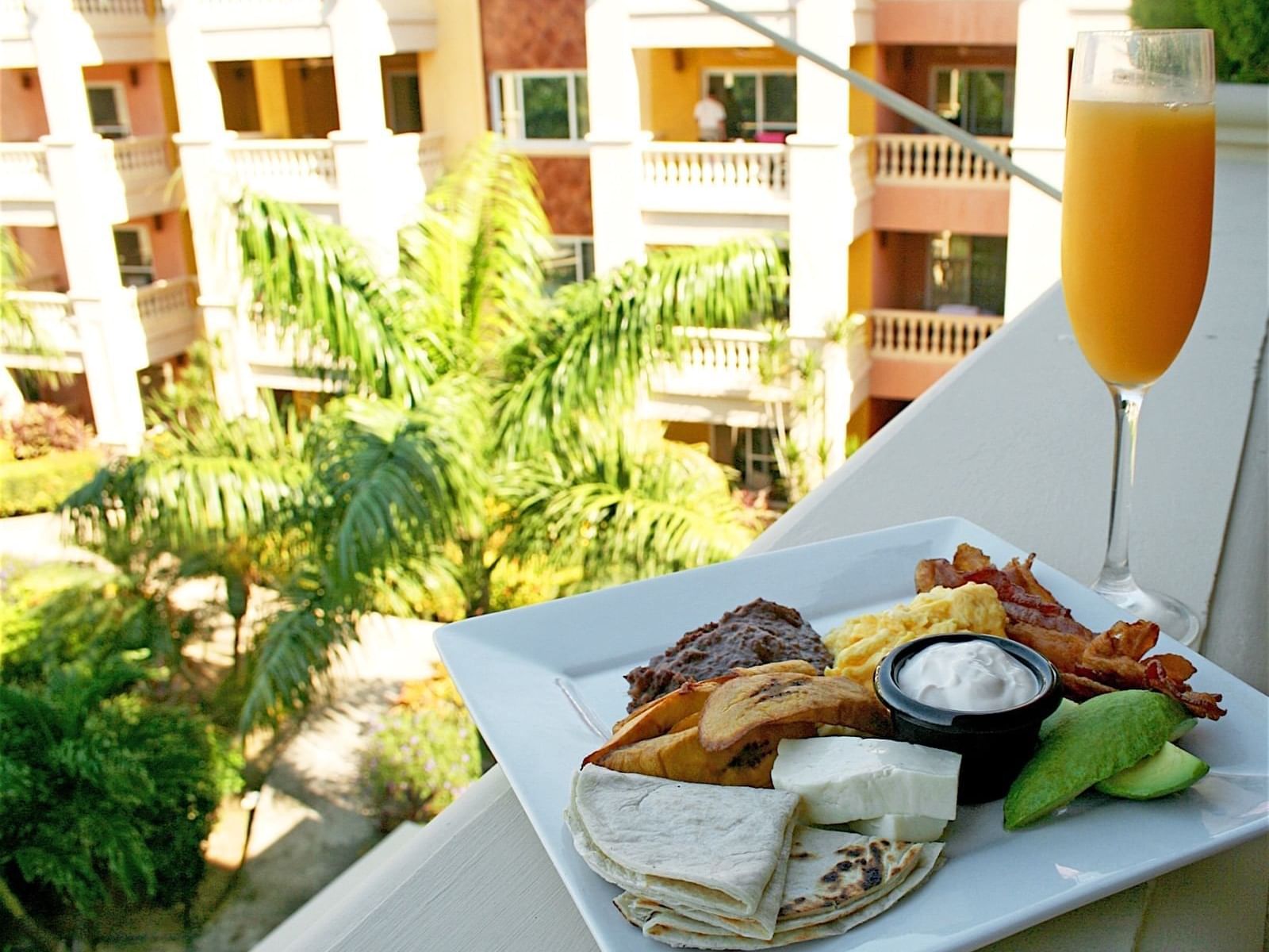 A food plate & a drink on a ledge of a balcony at Infinity Bay