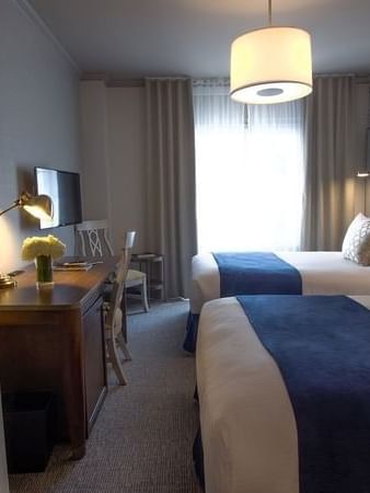 Twin Room features Two beds by a wooden desk under drum pendant lights at Warwick San Francisco