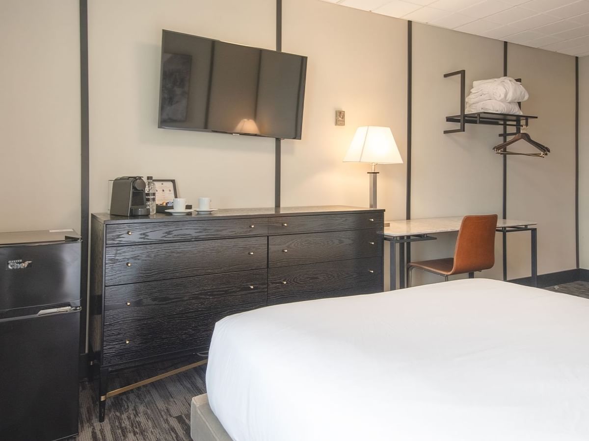 Hotel room with queen bed, mini fridge, chair, table, TV, and coffee