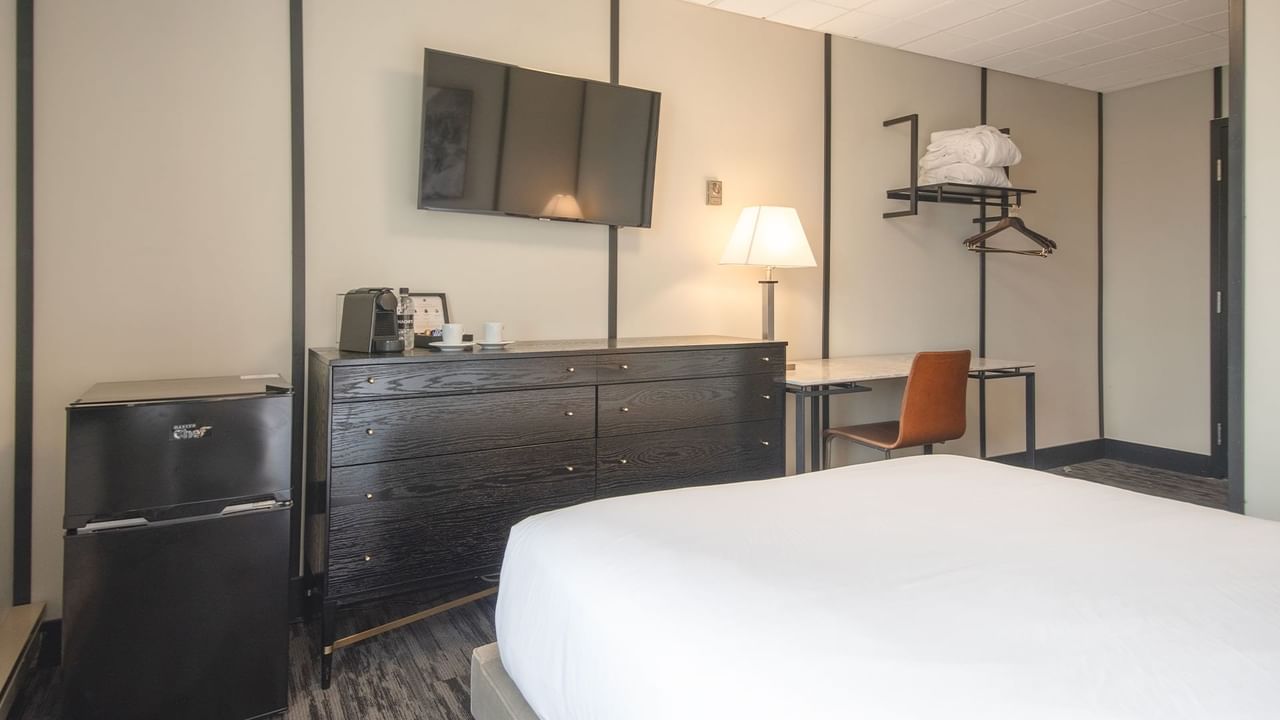 Hotel room with queen bed, mini fridge, chair, table, TV, and coffee