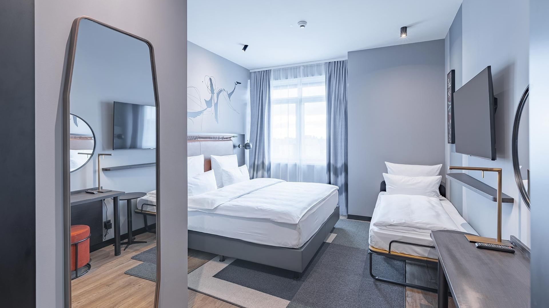 Room interior with cozy beds and TV in Classic Triple Room at Titanic Comfort Kurfürstendamm