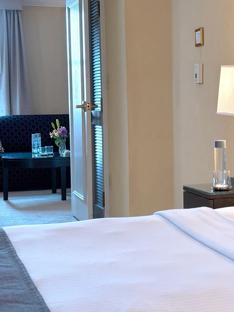 Bed with side table near door open to the living area in Superior Suite at Warwick Allerton Chicago