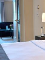 Bed with side table near door open to the living area in Superior Suite at Warwick Allerton Chicago