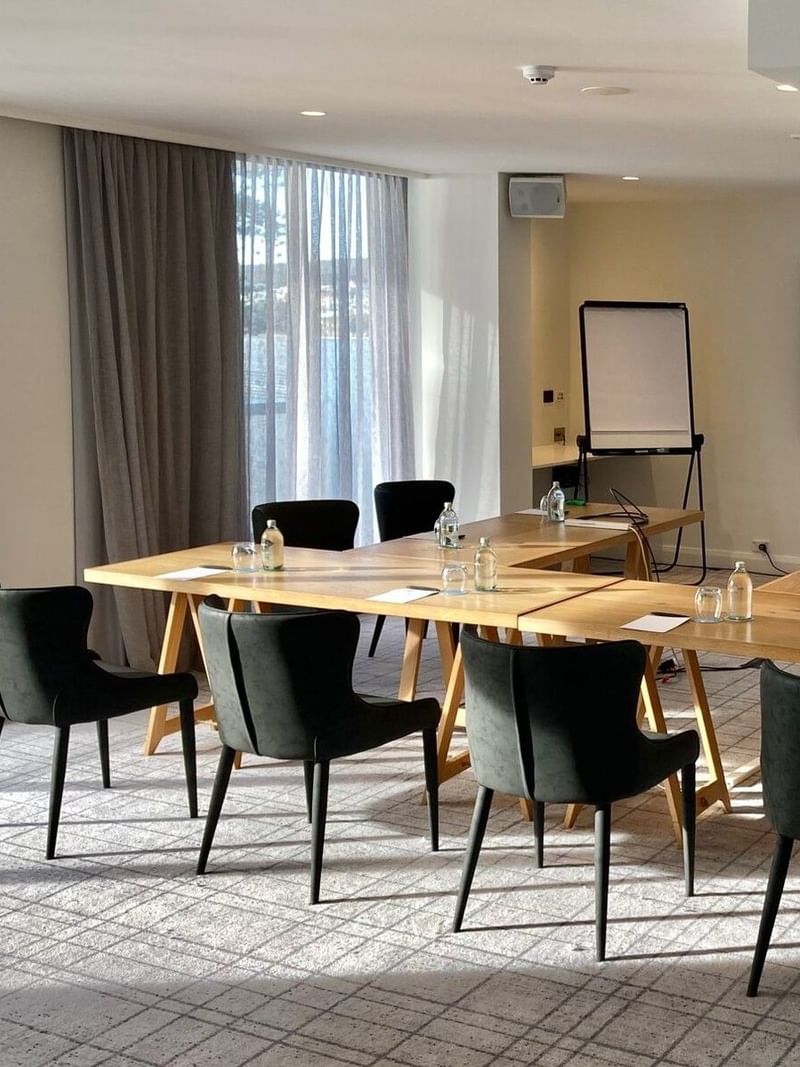 The Pacific Room at Elysium Manly with a U-shaped wooden table and black chairs near an interactive screen