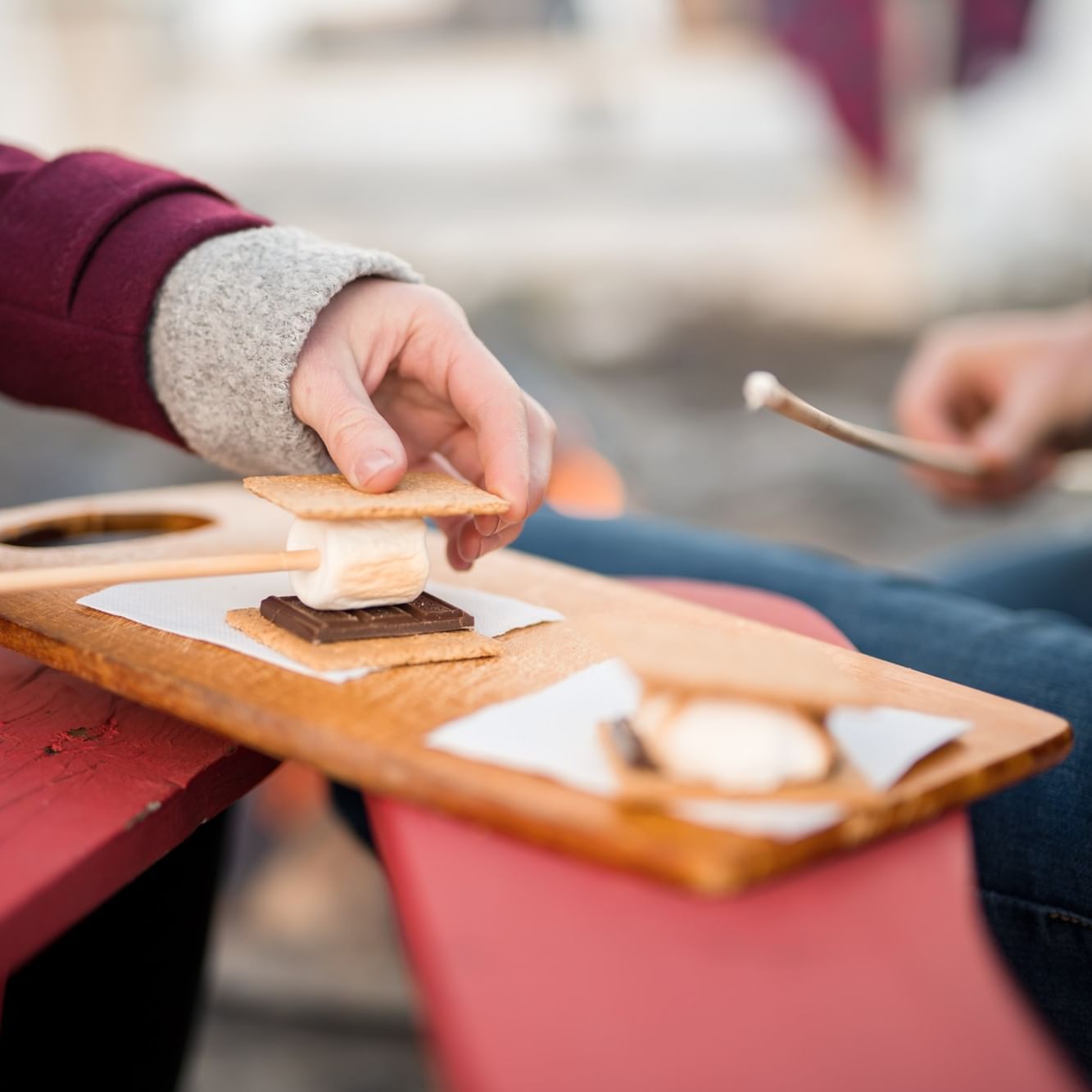 People roasting marshmallows on sticks over a fireside at Lake House.