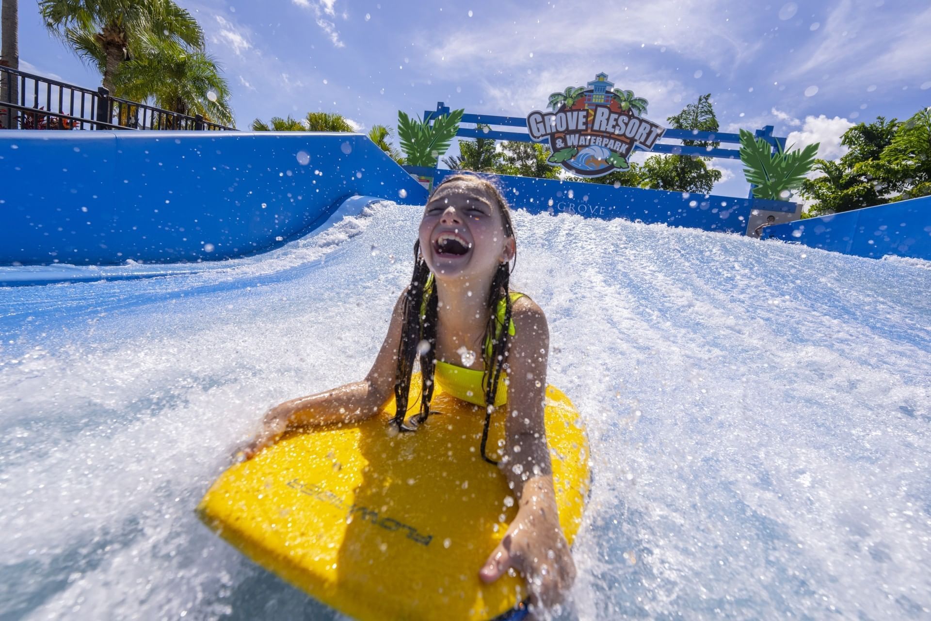 A girl sliding through a water wave on a sunny day at Surfari Water Park Resort