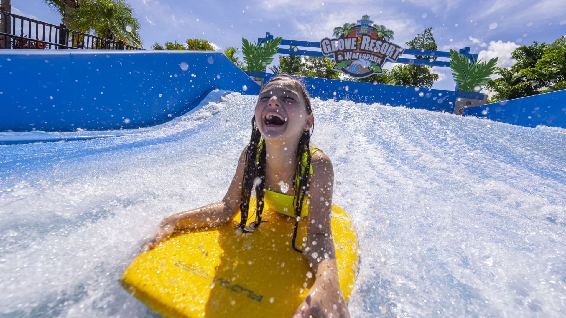 Young girl surfing on a yellow surfboard at Grove Resort & Waterpark.