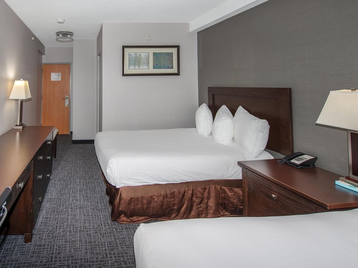 Two double beds with white linens in a room.
