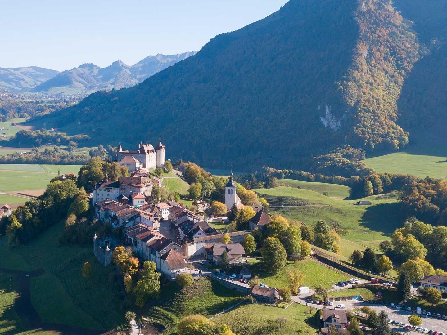 Aerial view of a Medieval city of Gruyeres nestled among rolling hills near Hotel des Innovations