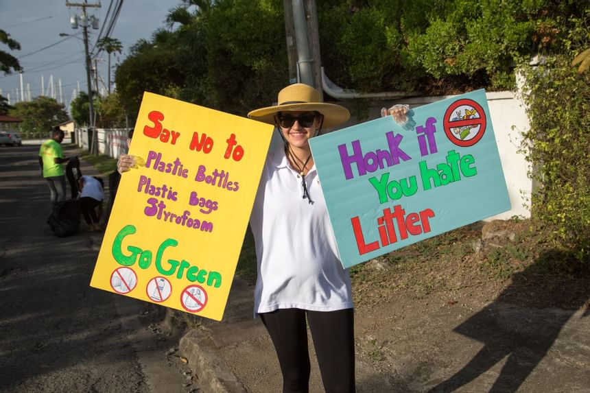 A person holding No litter signs near True Blue Bay Hotel