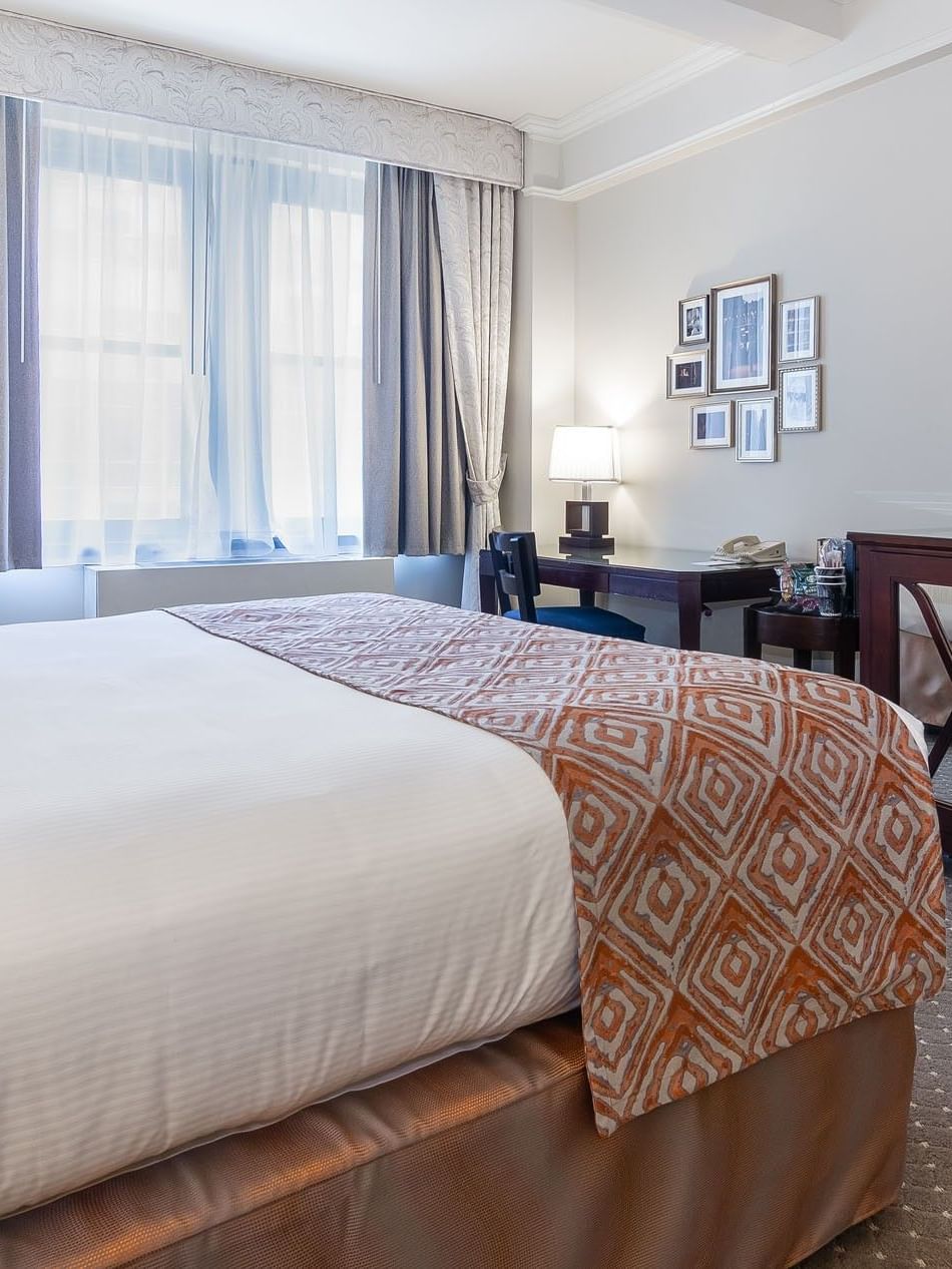 Bed facing a large television set beside work desk in Premier City View at Warwick New York