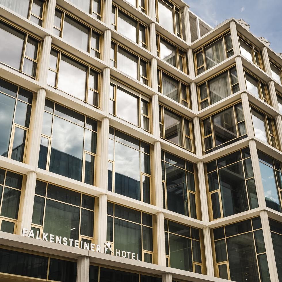 Fassade des Falkensteiner Hotels mit vielen Fenstern und goldenen Rahmen, teilweise Spiegelungen drin.