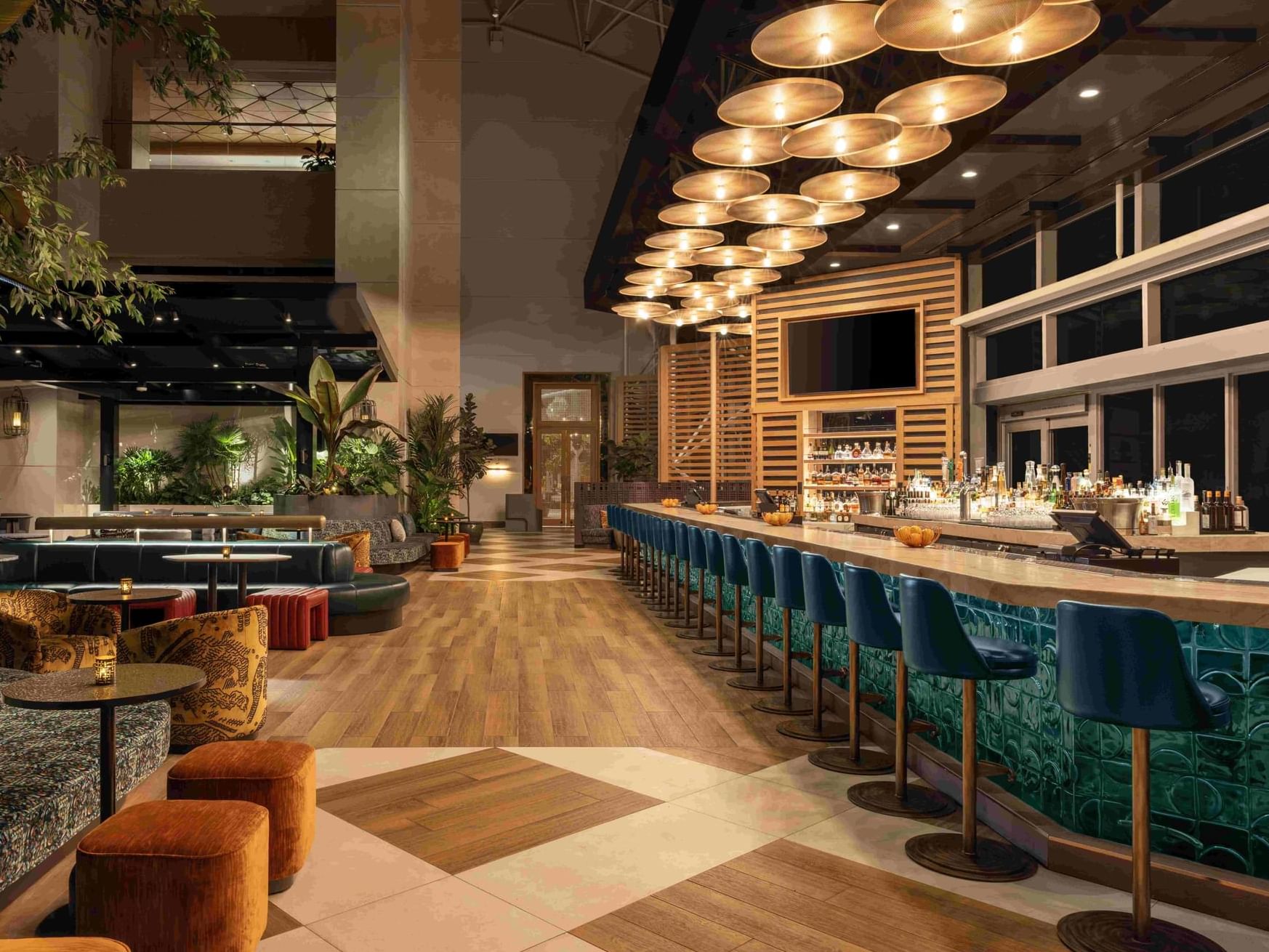 The Hotel Bar seating area with modern ceiling lights and accent chairs at The Diplomat Resort