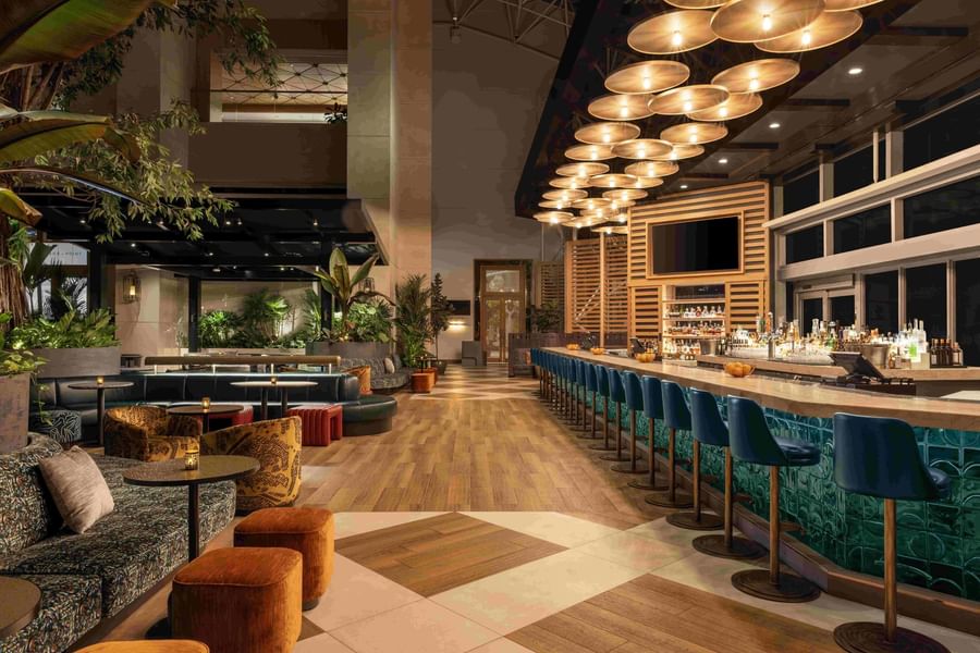 The Hotel Bar seating area with modern ceiling lights and accent chairs at The Diplomat Resort