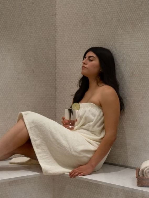 Guest in a towel by a cold drink under mosaic tiles at Warwick Melrose Dallas