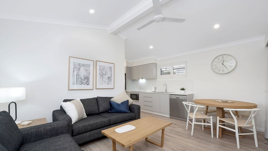 Deluxe Bungalow 2 Bedroom living space featuring a sofa, table, dining area, and kitchen at Mercure Hotel Townsville