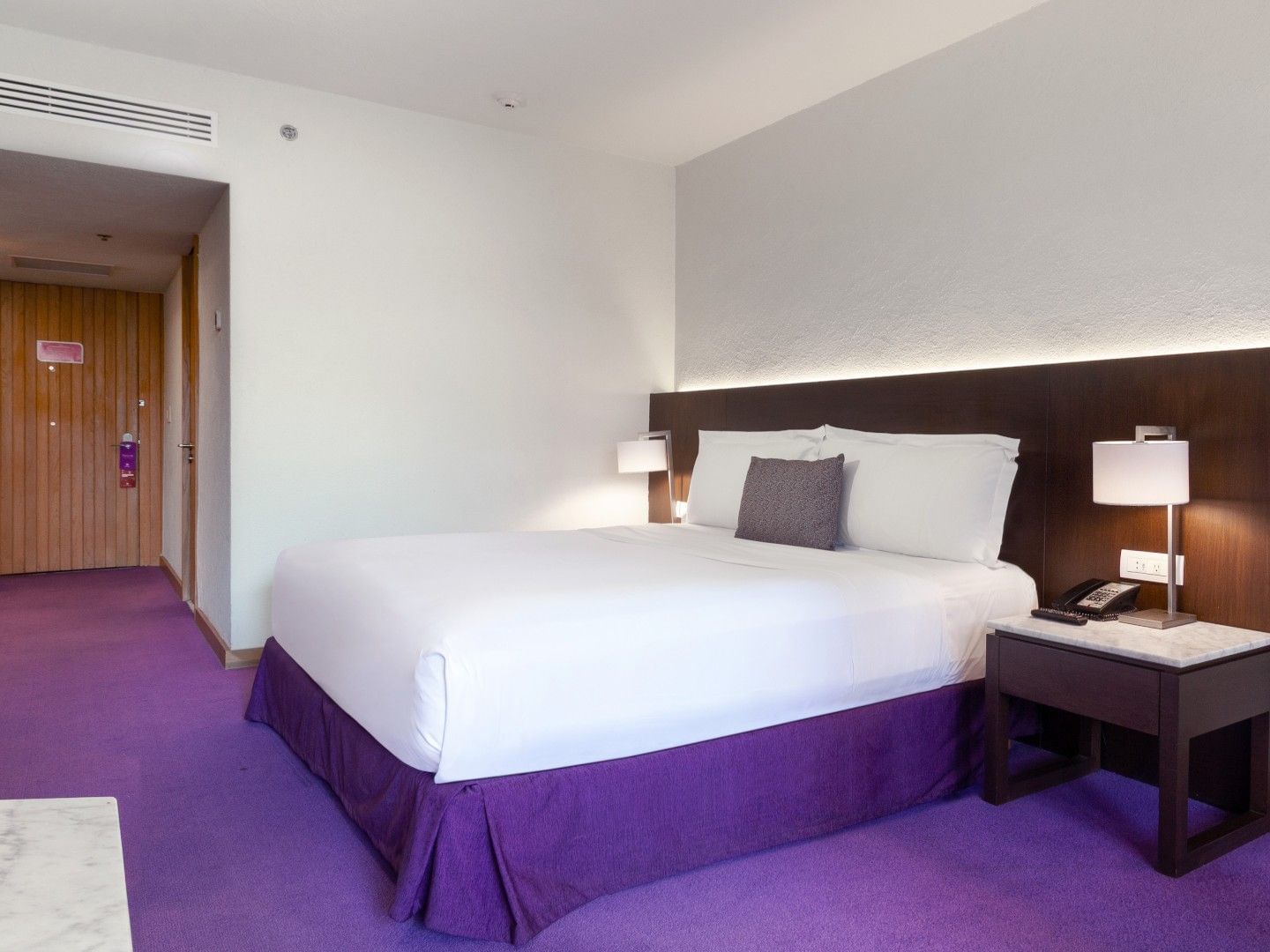 King Superior Deluxe room at Camino Real Polanco Mexico, with a purple carpet, dark headboard, and a bedside lamp