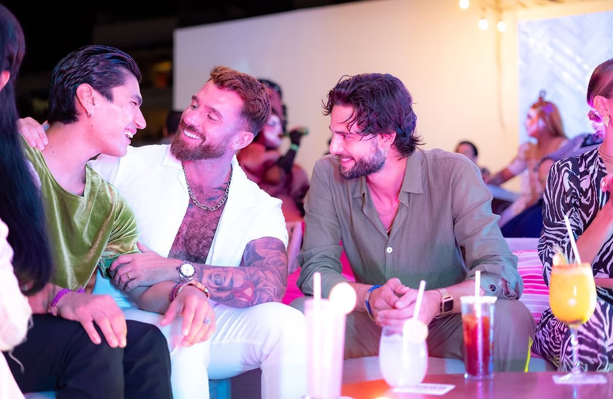 Group of people sitting at a table with drinks in The Top Sky Bar at Almar Beach Resort