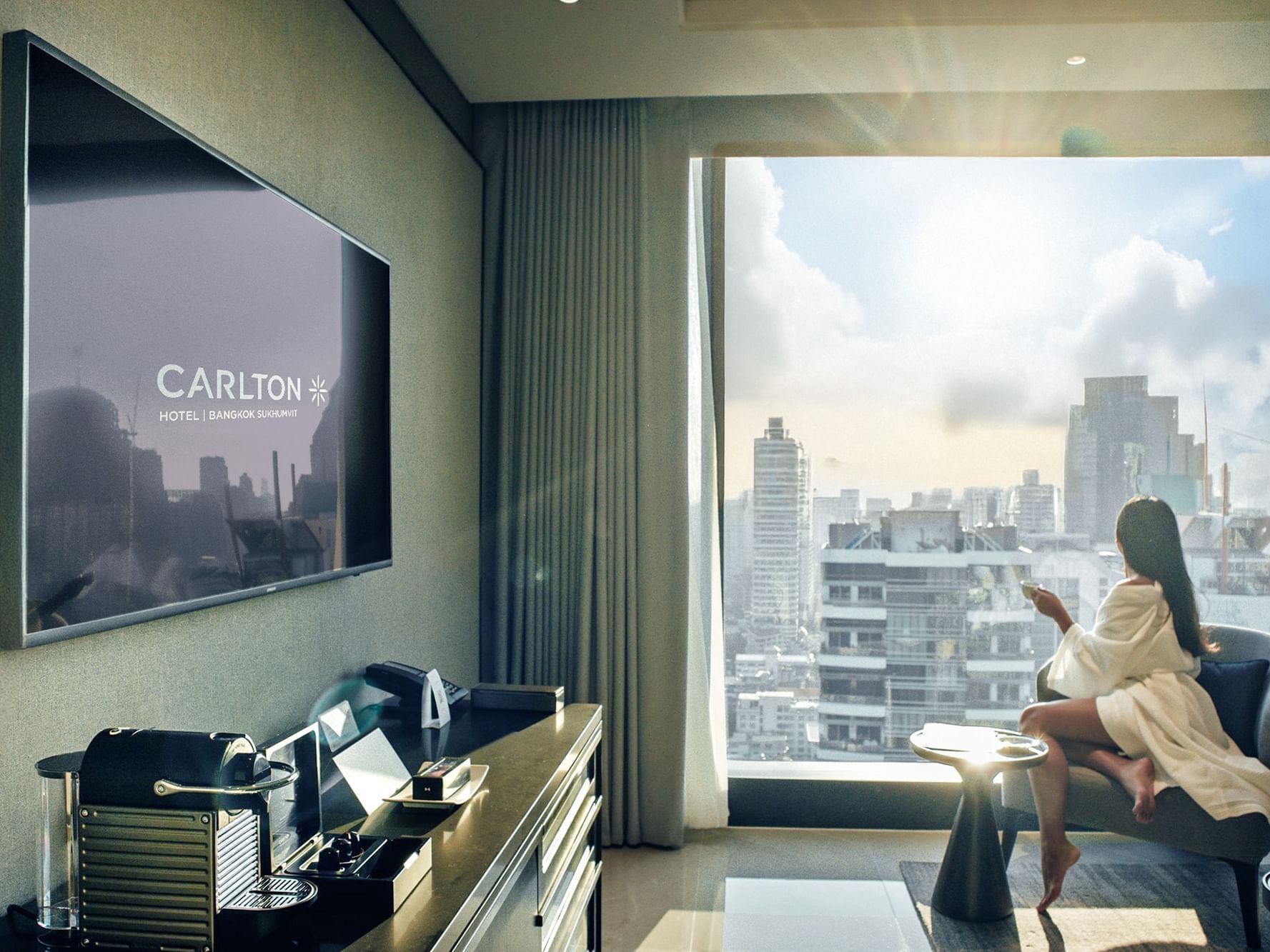 Lady relaxing on a lounge by the window overlooking the city on a sunny day at Carlton Hotel Bangkok Sukhumvit