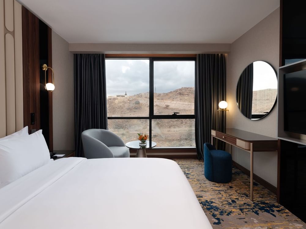 Bed with a couch and a work desk by the window in Deluxe Room at Warwick Al Taif Hotel