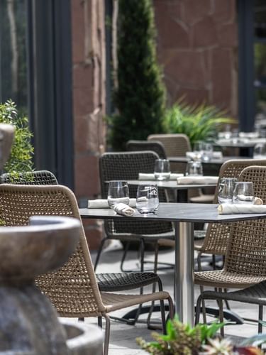 Chairs by tables with glass tumblers surrounding a stone water fountain in Gattara Restaurant & Patio at Warwick Denver