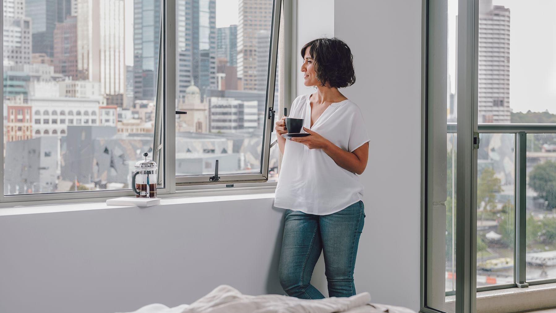 Lady standing by the window in 1 Bedroom Deluxe Apartment with City & River Views at Quay West Suites Melbourne